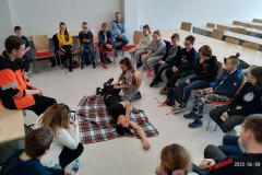 Dziewczynka  układający poszkodowanego w pozycji bezpiecznej
