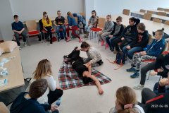 dzieci siedzące w półkolu  na środku poszkodowany